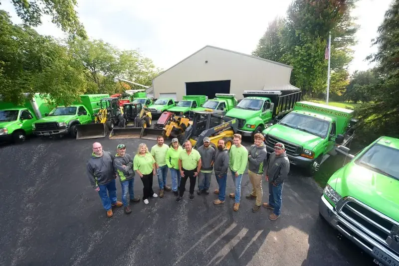 The Turf & Tree Worx team in front of their green trucks and equipment