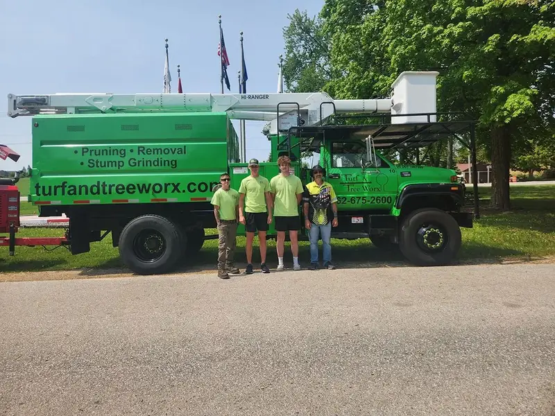 Turf & Tree Worx crew members beside their bucket truck